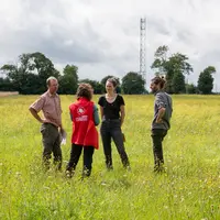 groupe de quatre personnes discutant dans une prairie