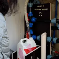 Femme avec un bidon devant machine à collecter urine