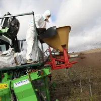 Salarié agricole apportant de l'engrais organique sur une parcelle de vigne en bio.