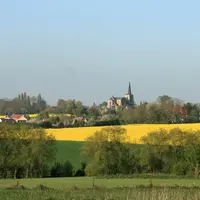 Paysage rural au printemps. village et terres agricoles. clocher. assolement. colza en fleurs et céréales. haie d'arbres. maison. maisons. habitat rur