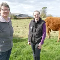 Eleveuse et sa fille devant des vaches limousones dans un pré.