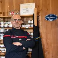 agriculteur en uniforme de pompier devant des produits locaux