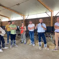 Visite chèvrerie, hommes et femmes dans bâtiment d'élevage caprin