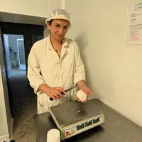 Fromagère qui coupe un fromage au-dessus d'une balance