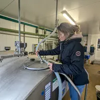 éleveuse de chèvres en train de rebrancher son tank à lait