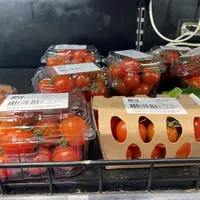 Barquettes de tomates cerise avec au premier plan une barquette en plastique et une en carton.