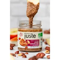 Une cuillère vient de plonger dans un pot de pâte à tartiner Amandes caramélisées au chaudron à marque Manger Juste