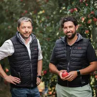 Deux producteurs de pommes posent dans leur verger