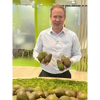 Zac Bard président de la WAO sur un stand à Fruit Logistica tient dans ses mains des avocats