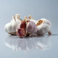 De l'ail blanc et violet, sur un fond uni bleu gris où se reflètent les gousses.
