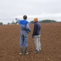 Agriculteur et salarié agricole discutant dans un champ des travaux à effectuer, novembre 2023