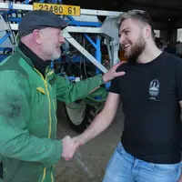 agriculteurs, un cédant un repreneur, qui se serrent la main devant un tracteur