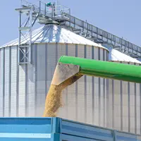 Céréales versées dans une benne avec des silos en arrière plan