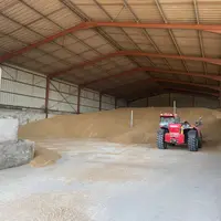 Stockage à plat sous hangar de blé à à la ferme avec un chargeur télescopique pour la manutention