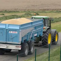 Tracteur sur la route avec une remorque remplie de grain de blé à livrer