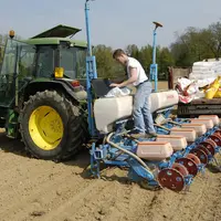un agriculteur et son apprenti travaillent sur un semoir dans un champ