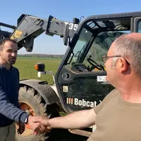 Poignée de main entre agriculteurs, en extérieur devant un téléscopique
