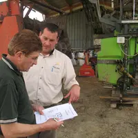 Agriculteur et conseiller préparant un contrôle sous un hangar.