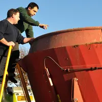 Eleveur donnant les instructions à son salarié. Agriculteur employeur. Transmission des consignes. Discussion près de la distr