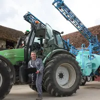 Agriculteur devant un pulvérisateur entrain de saisir des informations sur une tablette.