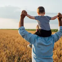 Agriculteur avec son enfant sur les épaules dans une champ de blé