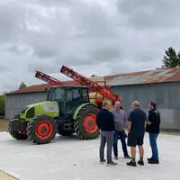 Contrôleur et agriculteurs devant un pulvérisateur.