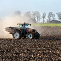 Epandage d'engrais Bio3G stimulateur de croissance qui augmente l'activité microbienne du sol sur un champ labouré a