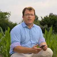 Damien Cariou fondateur et CEO de Syndev téléphone à la main dans un champ