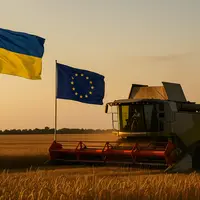 Une moissonneuse batteuse en action pour la moisson 2025 dans un champ de blé avec les drapeaux de l'Ukraine et de l'UE en arrière plan.