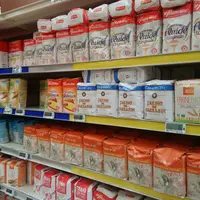 Rayon de supermarché avec des paquets de farine de toutes marques.
