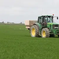 Tracteur qui épand des engrais dans un champ de blé.