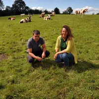 Nicolas Dumont, éleveur dans le Puy-de-Dôme, et Géraldine Dupic, conseillère fourrages, accroupis dans une prairie