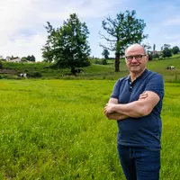 L'éleveur Jean-Michel Javelle devant une prairie avec son troupeau de vaches laitières.