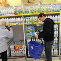 Vente de lait de vache en grande distribution. Achat de lait UHT par des clients de supermarché. Consommateur au profil de célibataire choisissant un
