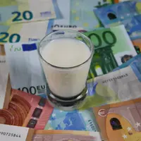 Milk price and agricultural products trend concept: Small glass of milk on euro money bank notes