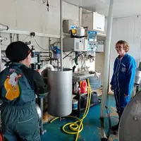 Une éleveuse et une personne en visite sur la ferme dans le bloc traite.