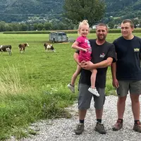 Deux éleveurs avec une petite fille devant un près avec des montbéliardes en Haute-Savoie