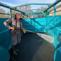 Agriculteur qui nettoie une bétaillère avec un nettoyeur haute pression.