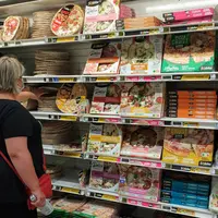 femme au rayon pizza d'un supermarché