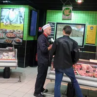 deux hommes discutent au rayon boucherie du supermarché