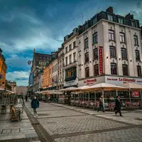 un groupe de personnes marchant dans une rue à côté de grands immeubles