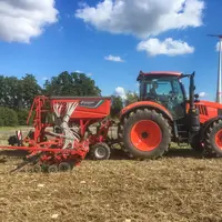 Semoir Kverneland dans un champ avec un tracteur Kubota