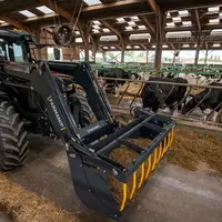 Tracteur avec chargeur frontal Farmanip dans un bâtiment d’élevage avec des vaches.