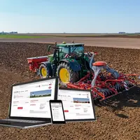 Tracteur John Deere réalisant un chantier de semis avec du matériel Kuhn