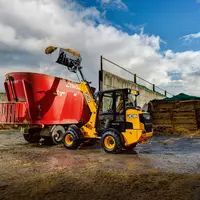 Valet de ferme chargeuse articulée télescopique JCB TM110 chargeant une mélangeuse Trioliet