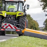 Rotobroyeuse Noremat derrière un tracteur Claas, réalisant des travaux de fauchages.