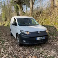 Fourgonnette Volkswagen Caddy Cargo dans un chemin de terre recouvert de feuille