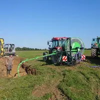 Chantier de nettoyage des drains incluant une mini-pelle Neuson, un nettoyeur de drain Sieger, attelé à un tracteur Case IH, e