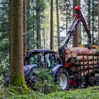 Débardeuse HORSCH PIRK Forestry devant un tracteur dans la forêt.