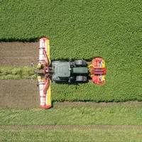 Vue du ciel d'une combinaison de faucheuses Pöttinger avec groupeur à vis sans fin
